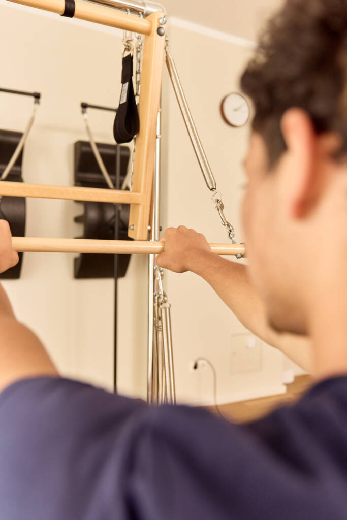 Junger Mann trainiert am Reformer im Makeda Pilates Studio Berlin im Prenzlauer Berg